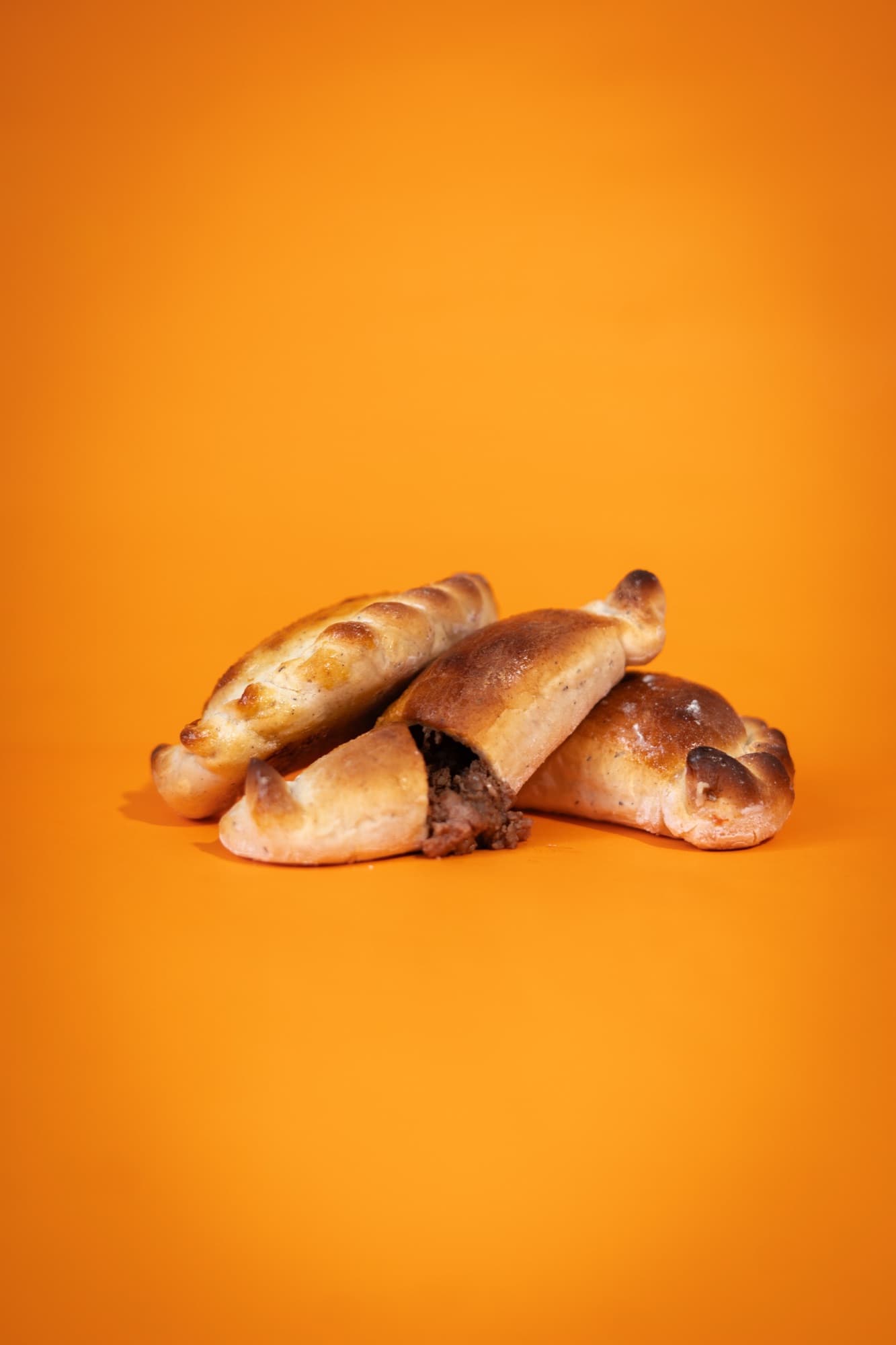 Empanadas de carne recién horneadas, una abierta mostrando el relleno