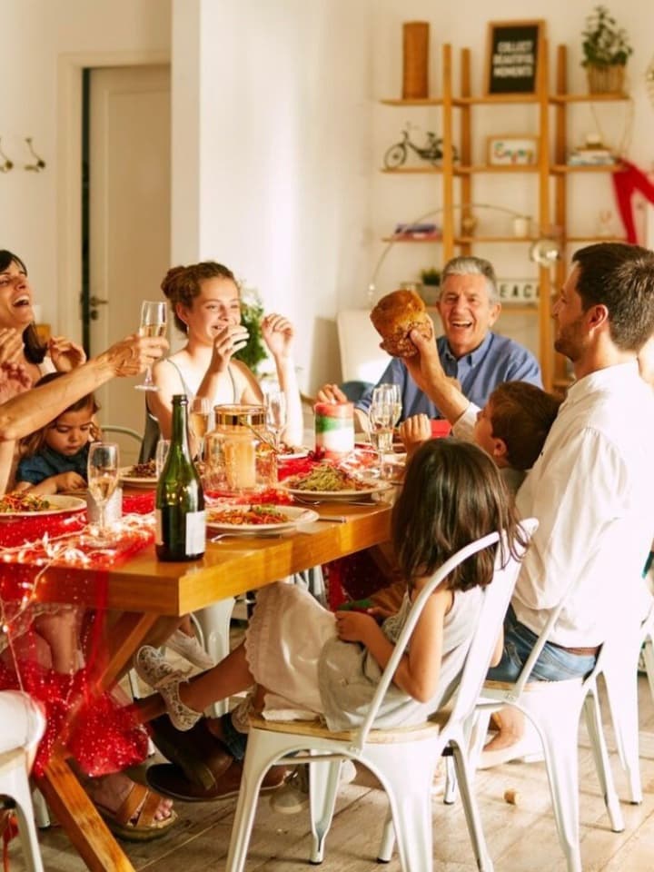 Familia y amigos brindando y compartiendo una comida alrededor de una mesa