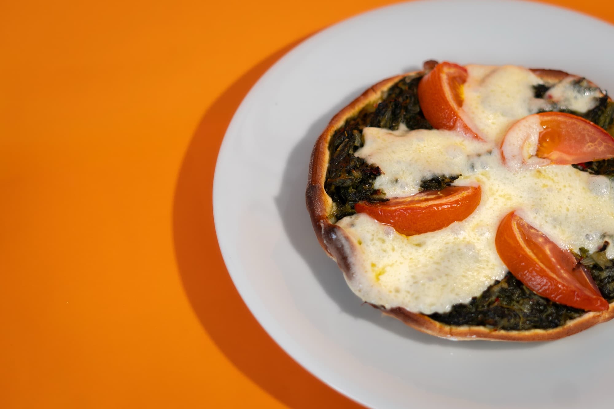 Tarta de verdura con tomate y queso gratinado en un plato blanco